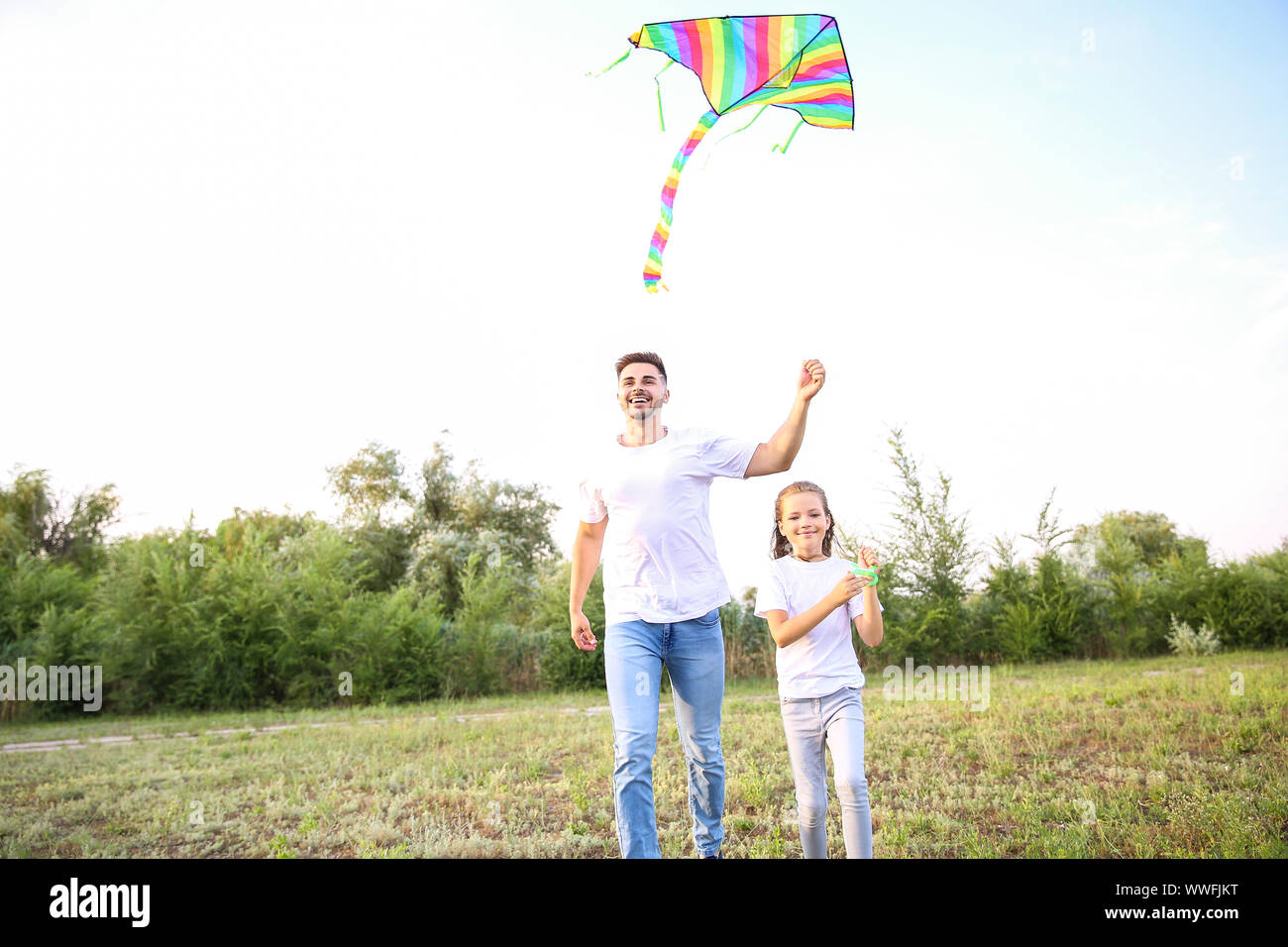Young man with little daughter flying kite outdoors Stock Photo