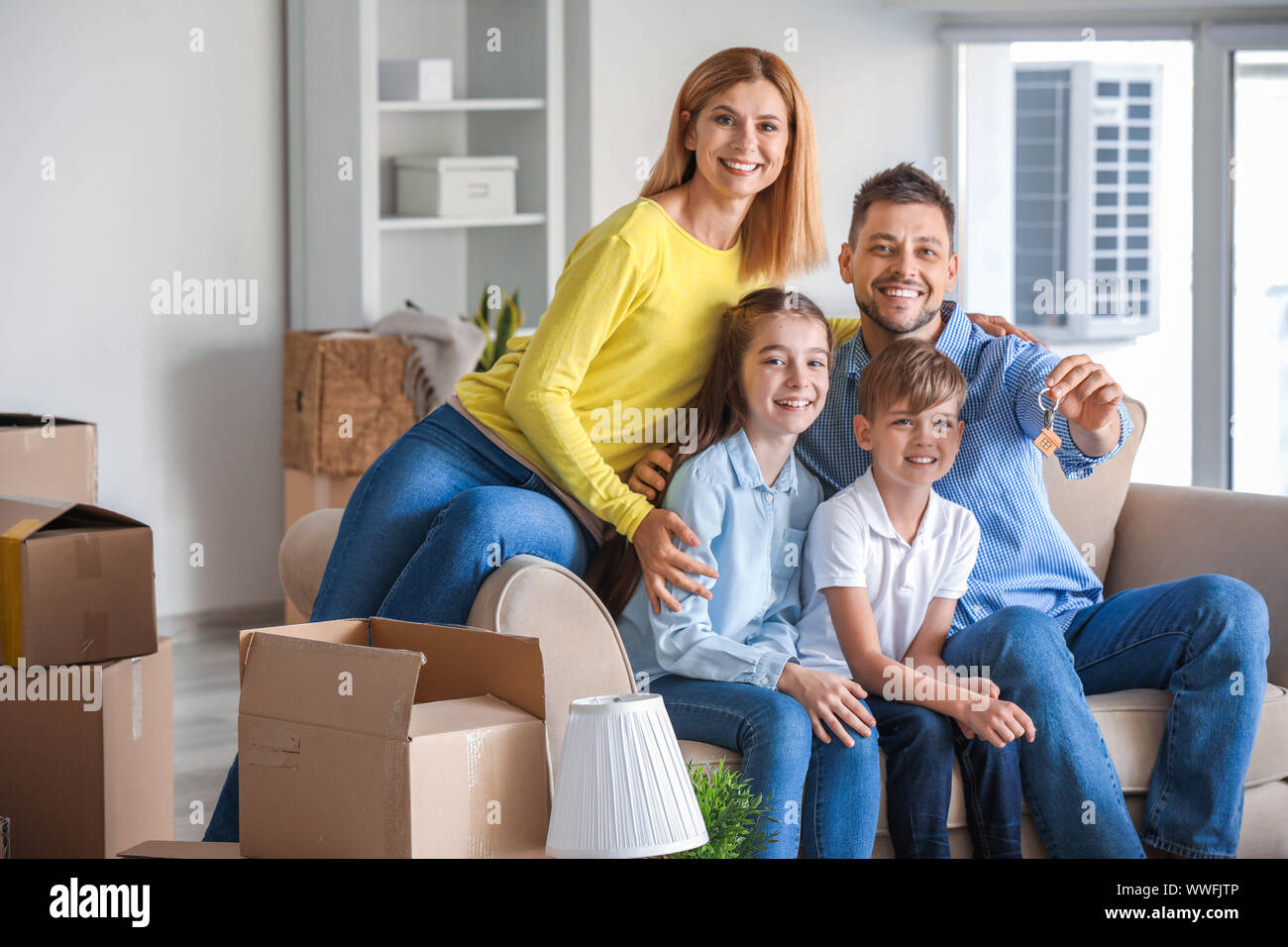 Happy family with belongings and keys in their new house Stock Photo ...