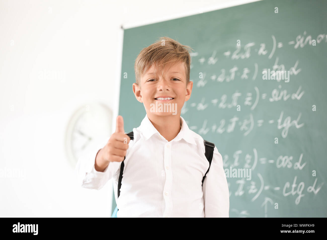 Cute little schoolboy showing thumb-up in classroom Stock Photo - Alamy
