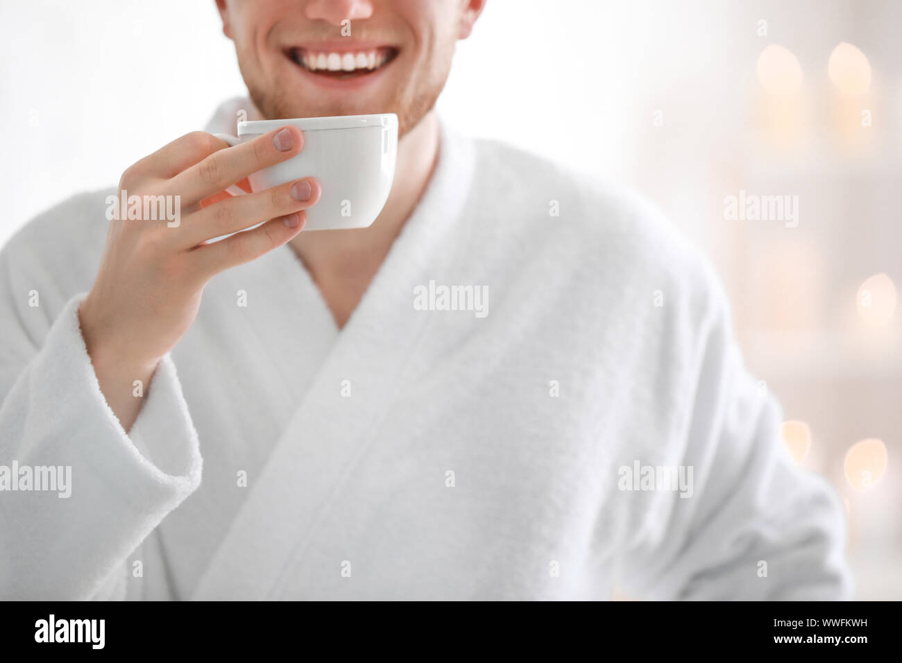 Young man in bathrobe drinking coffee at home Stock Photo