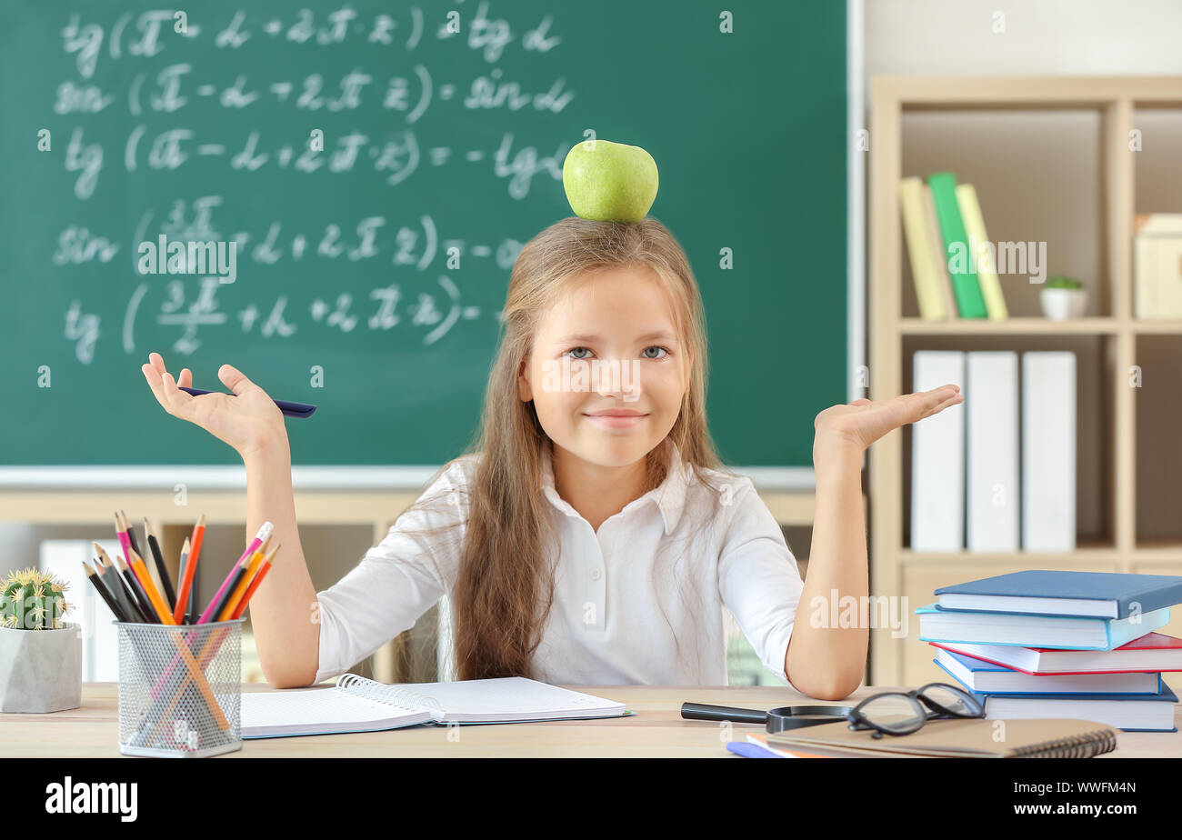 Little girl with apple sitting at desk in classroom Stock Photo - Alamy
