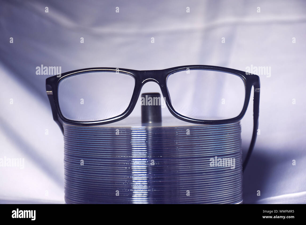one eye glasses on the Stack of empty disks with grew cloth background. Stock Photo