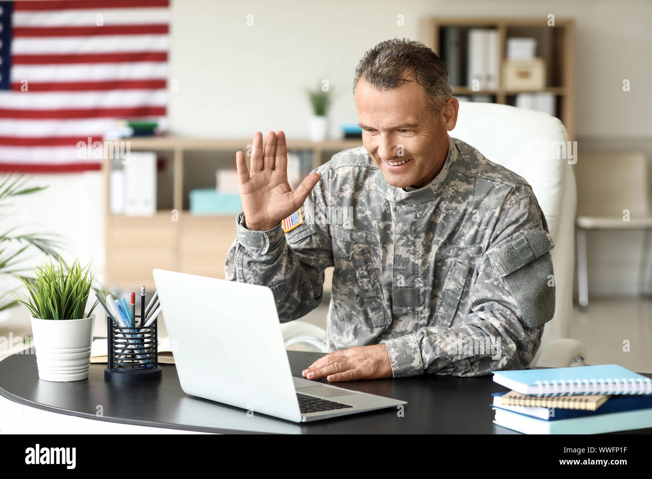 Mature male soldier using laptop in headquarters building for ...