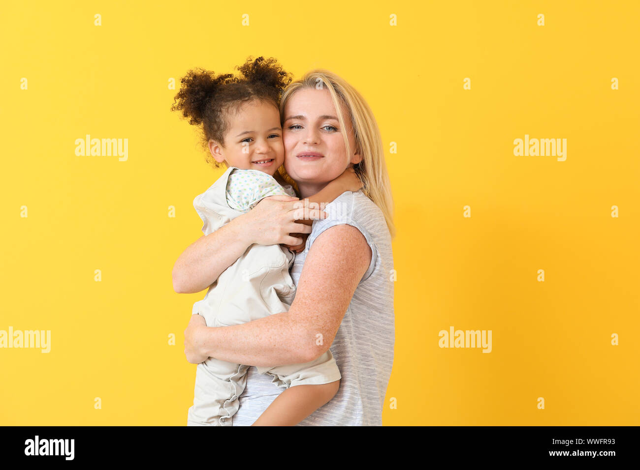 Happy woman with her little African-American daughter on color ...