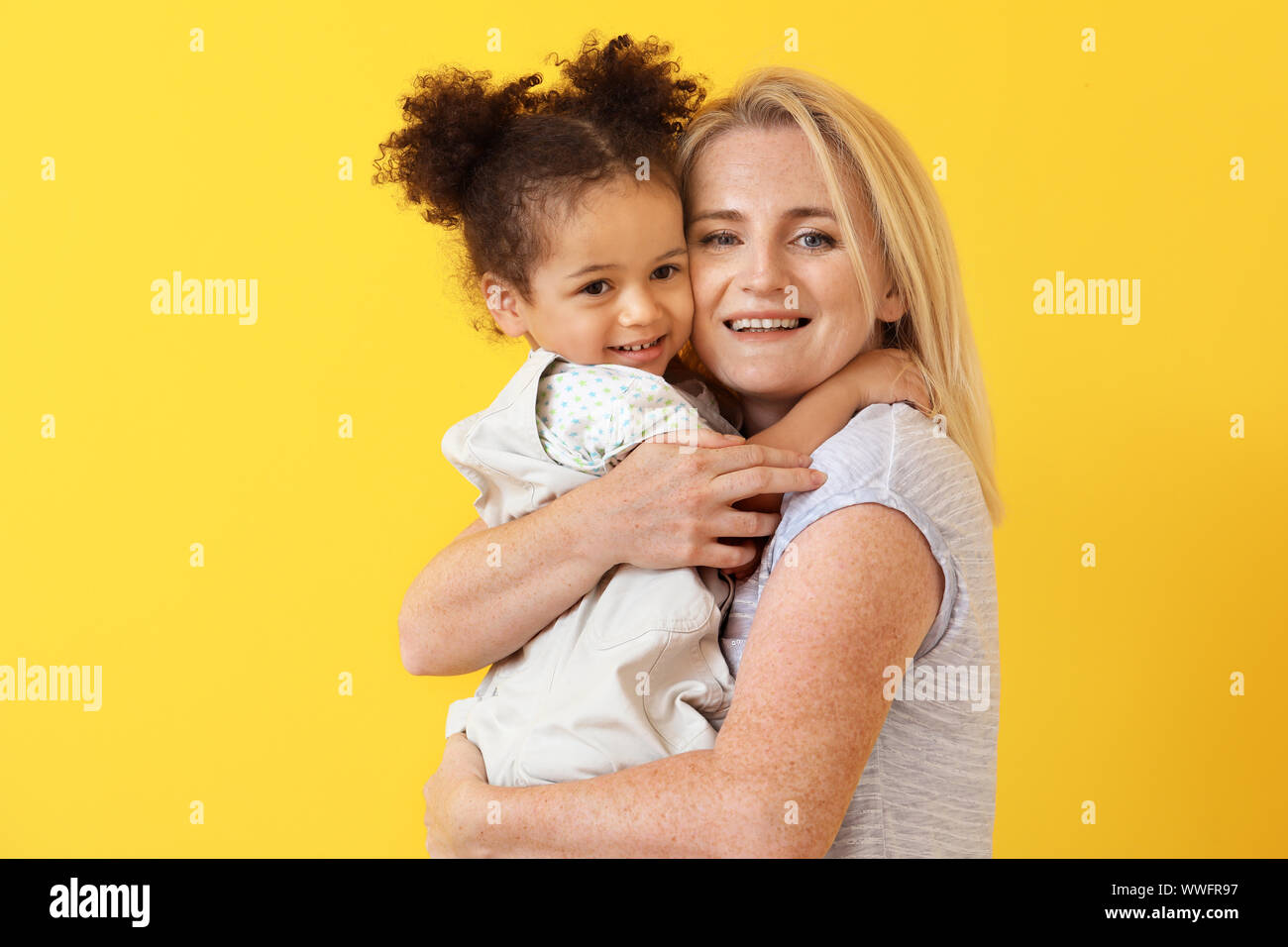 Happy woman with her little African-American daughter on color ...