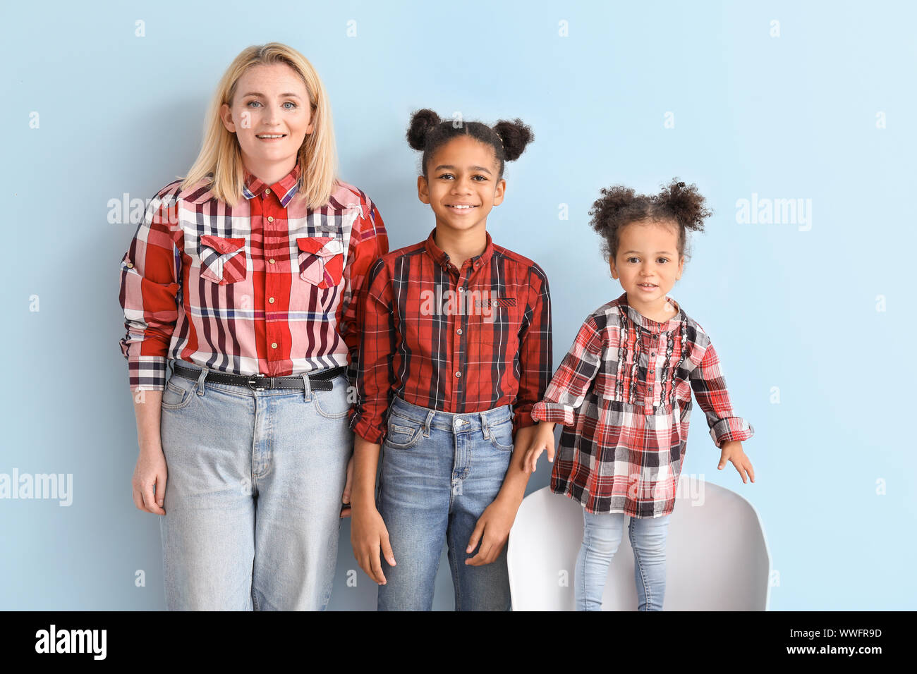 Happy woman with her African-American daughters on color background ...
