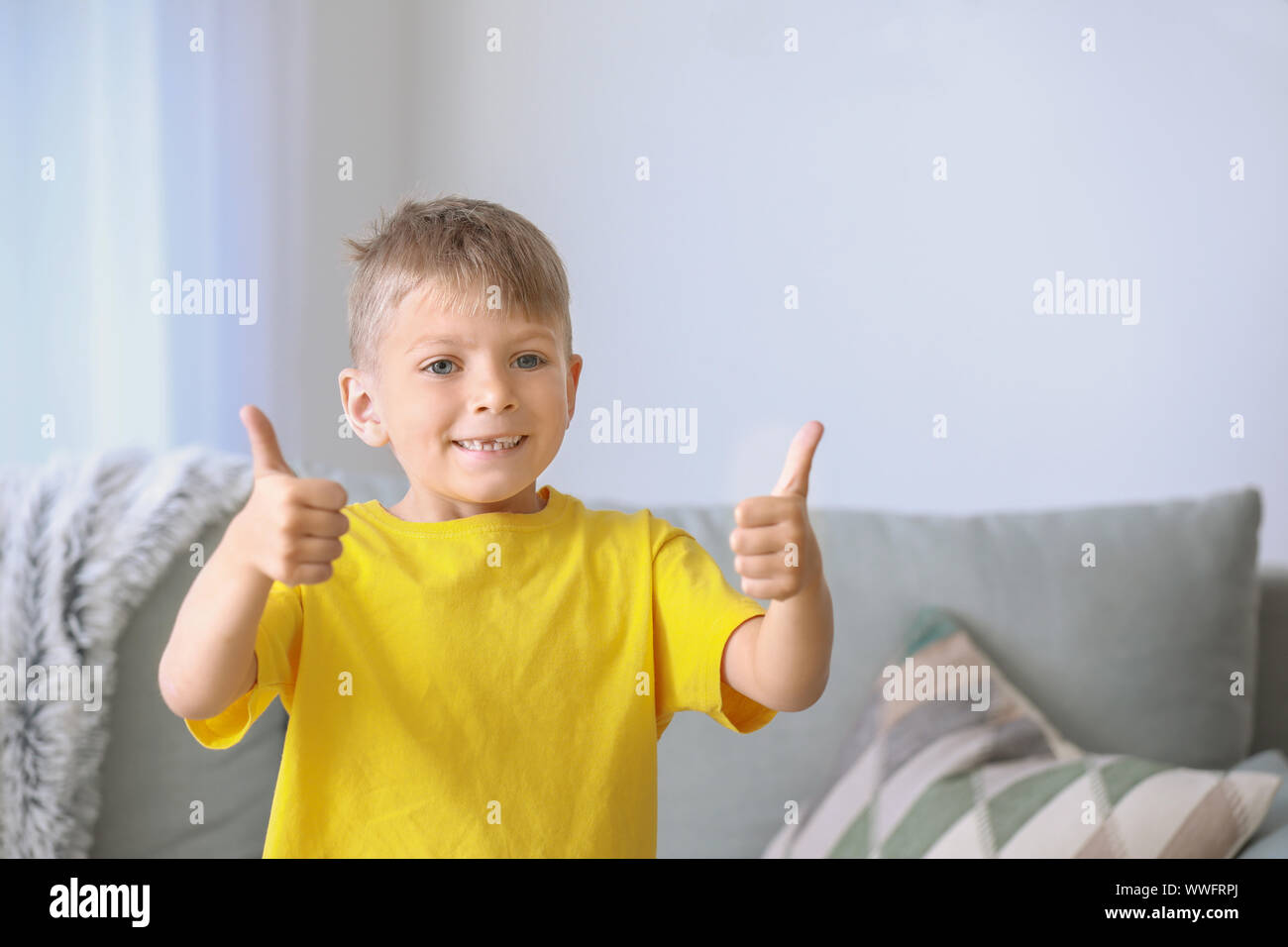 Cute little boy showing thumb-up gesture at home Stock Photo - Alamy