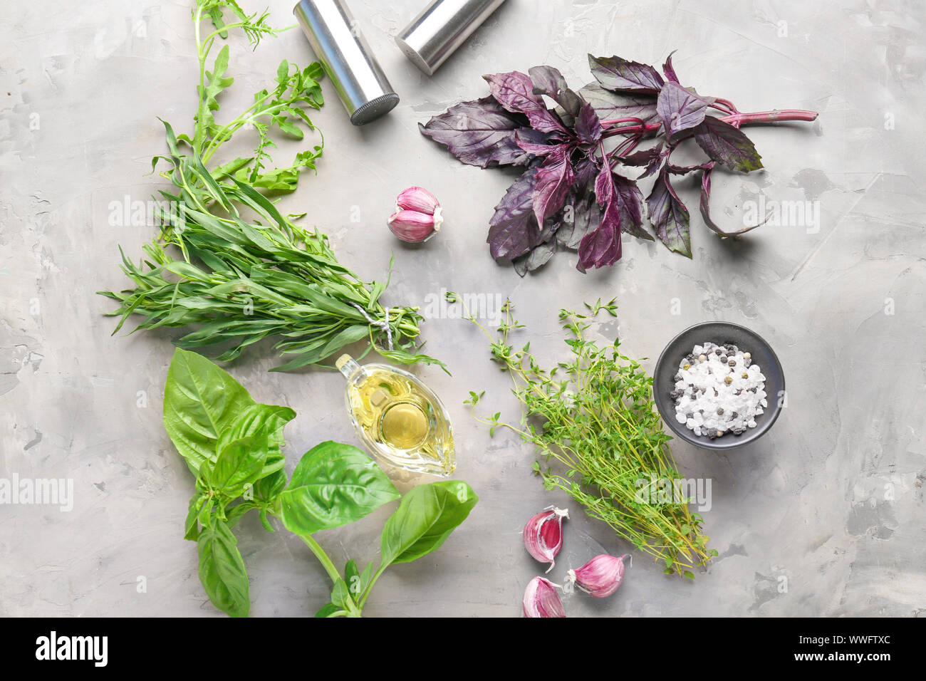 Different fresh herbs with oil, salt and garlic on grunge background ...