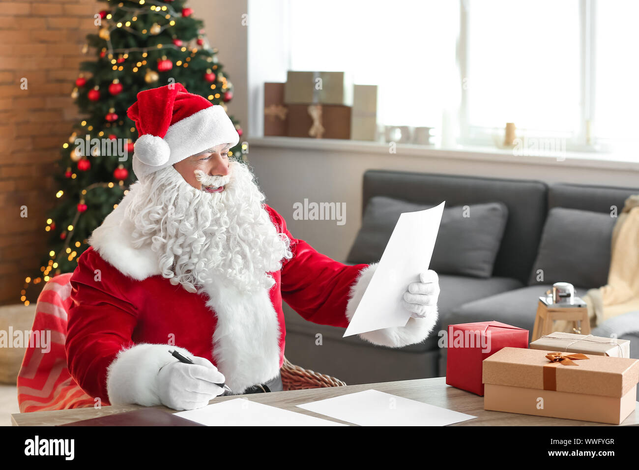 Santa Claus reading wish list in room decorated for Christmas Stock ...