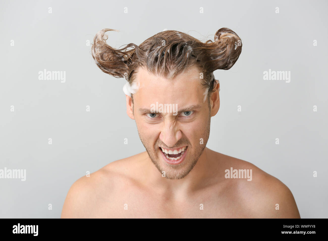 Funny Young Man Washing Hair Against Grey Background Stock Photo