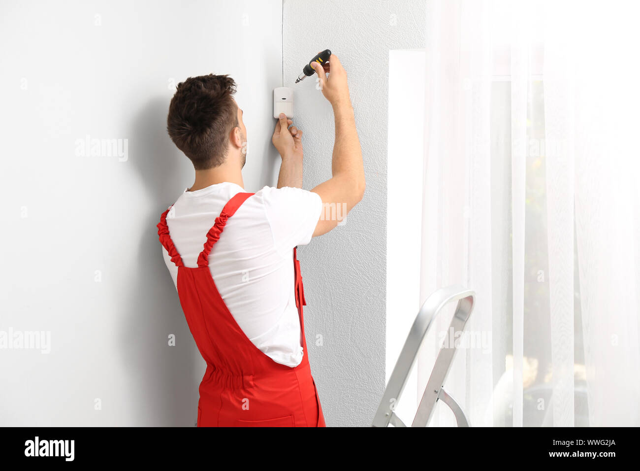 Electrician installing alarm system indoors Stock Photo