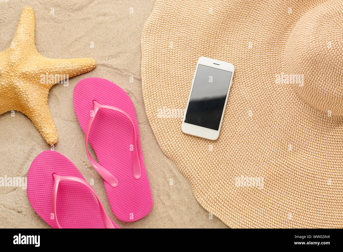 Flip-flops with mobile phone, hat and starfish on sand beach Stock ...