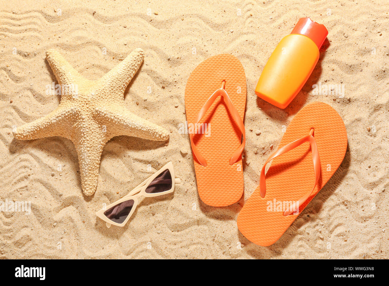 Flip-flops with sunglasses, cosmetics and starfish on sand beach Stock ...