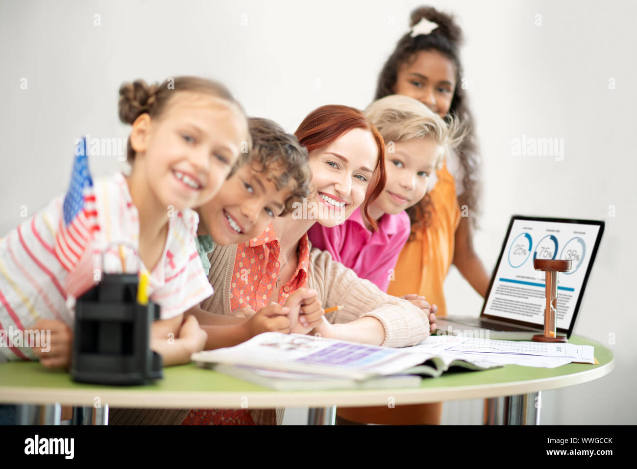 Teacher and children sitting at the table near laptop Stock Photo