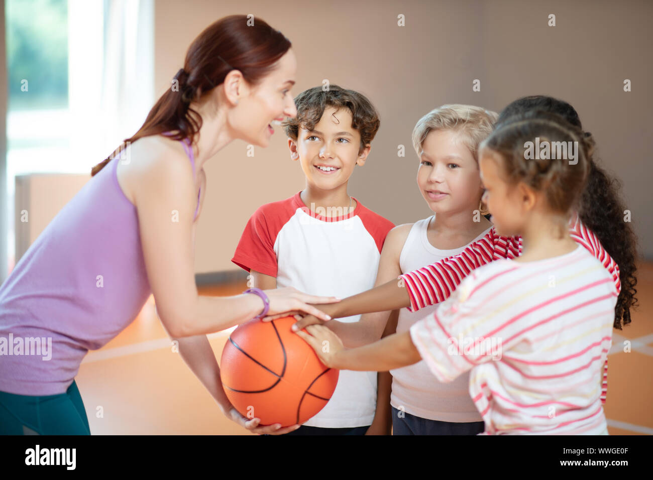 PE teacher and children smiling before starting basketball game Stock