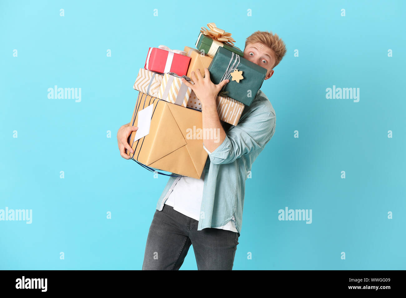 Young man with many gift boxes on color background Stock Photo