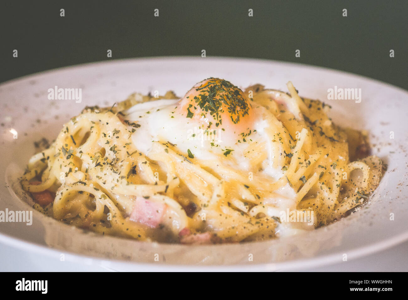 cheeszy smoked duck spaghetti pasta in white carbonara sauce topped with sous  vide egg and herb Stock Photo - Alamy