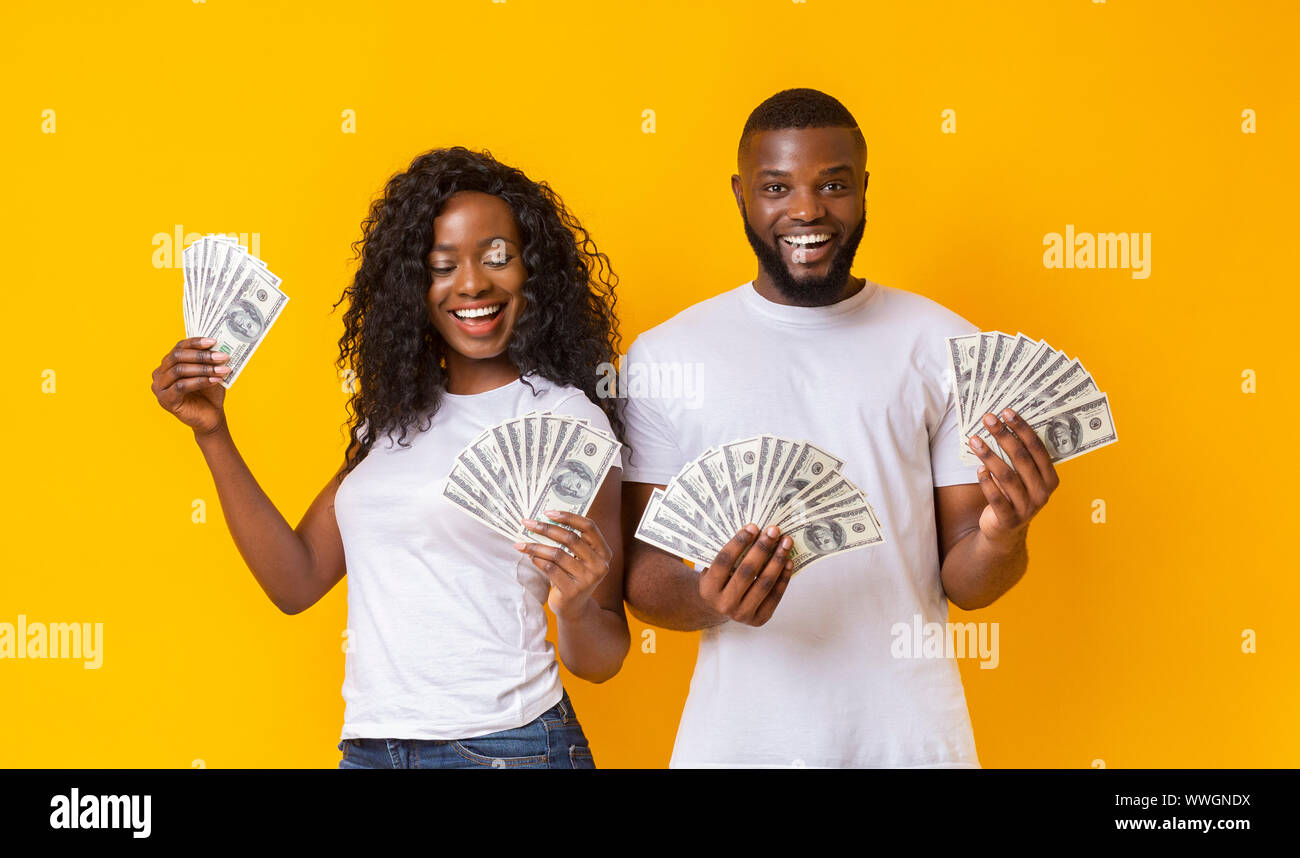 Cheerful black couple holding money and smiling Stock Photo - Alamy