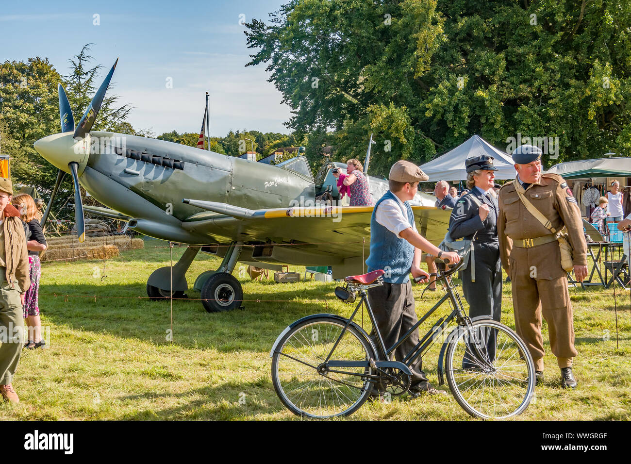 People dressed up in 1940s clothing posing in front of a World War 2 ...