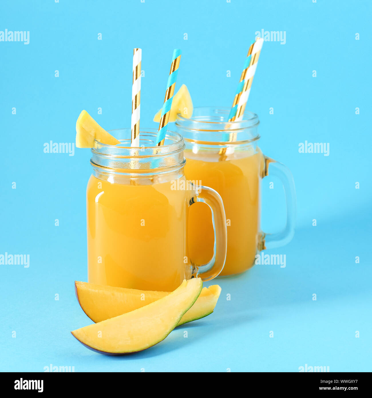 Mason jars of fresh mango juice on color background Stock Photo - Alamy