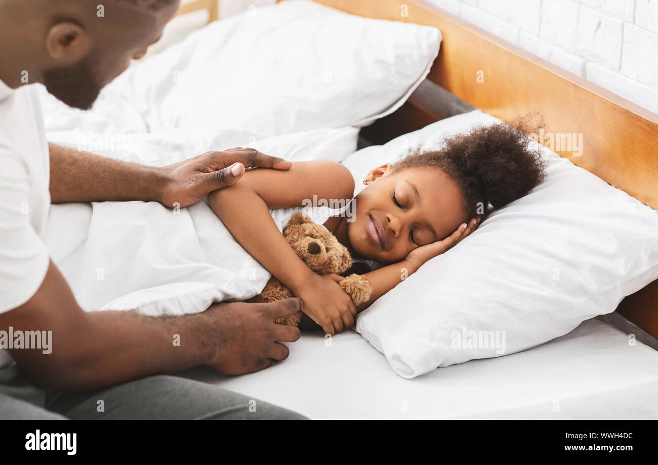 African dad covering his sleeping little daughter Stock Photo
