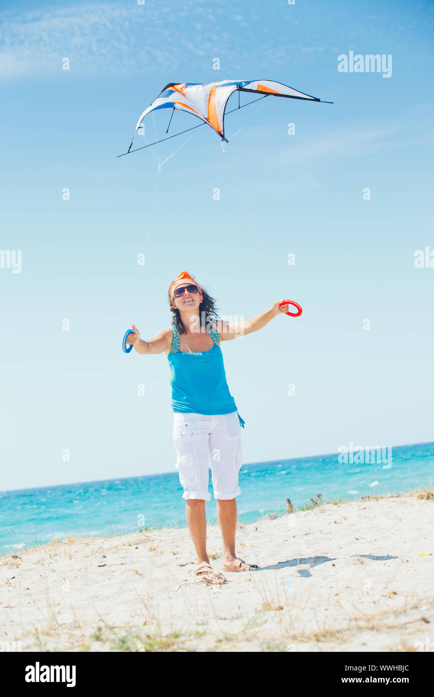 Young cute woman playing with a colorful kite on the tropical beach. Vertikal veiw Stock Photo
