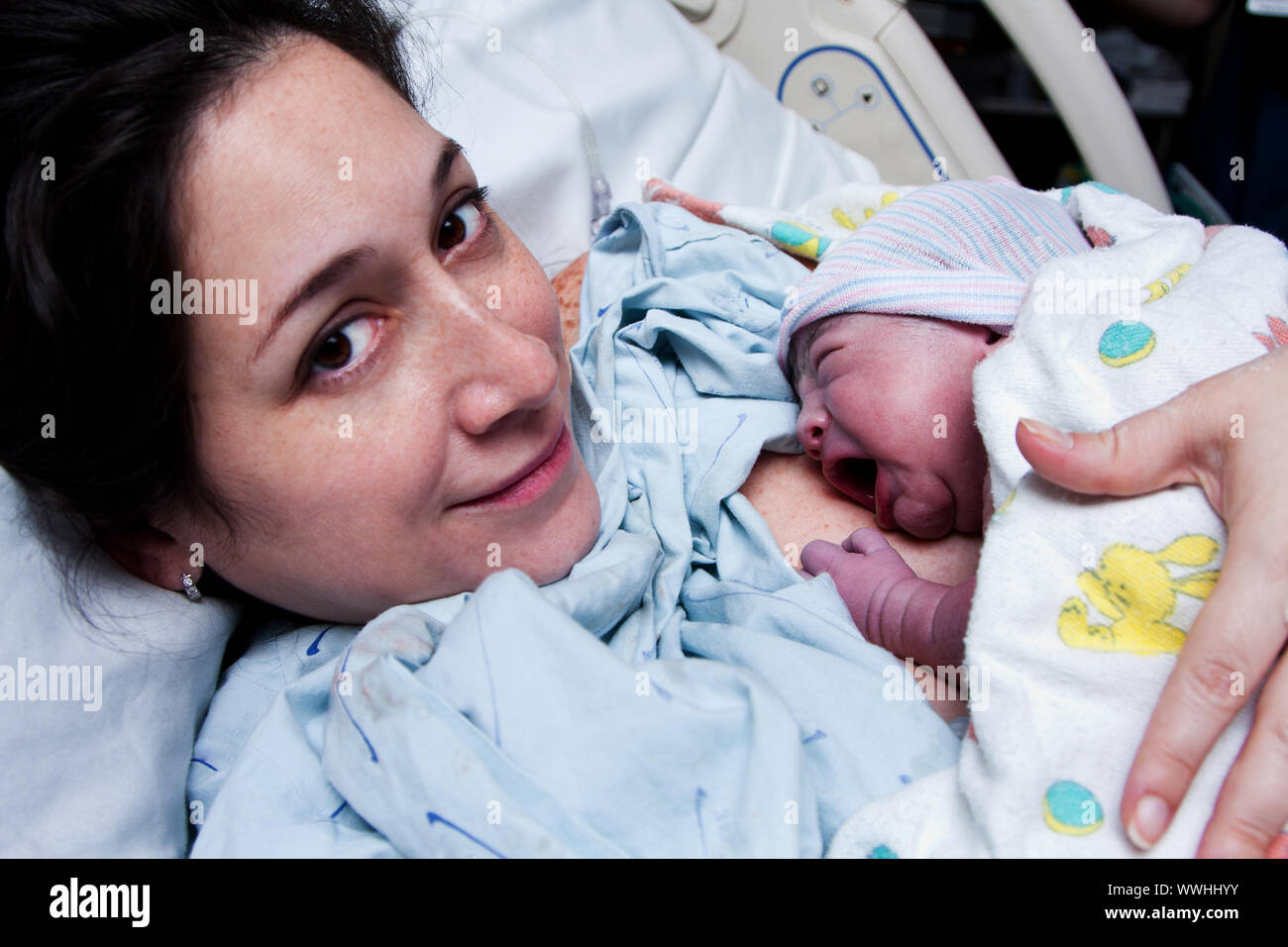 Beautiful new mother happy holding her infant baby after giving birth in hospital. Stock Photo