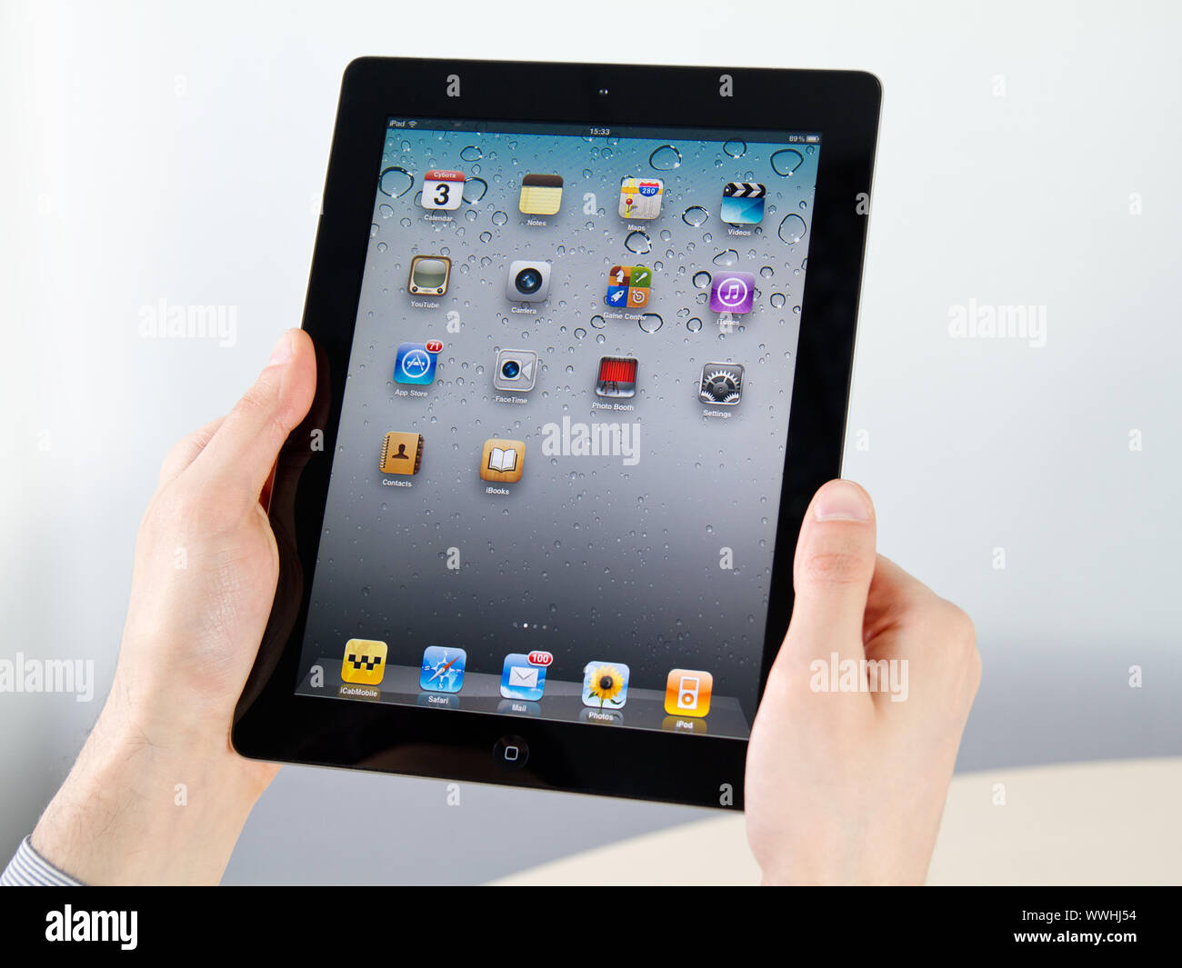 Kiev, Ukraine - December 03, 2011 - Man hands holding Apple iPad2 with homepage on a screen. This second generation iPad2 is designed and development Stock Photo