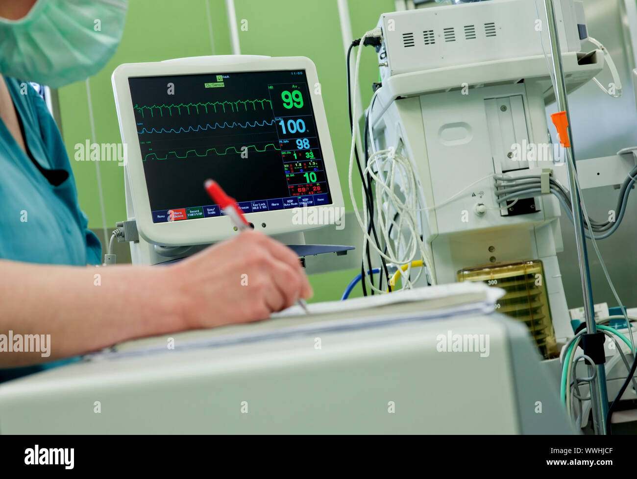 Cardiogram monitor in operative room, nurse writing down information ...