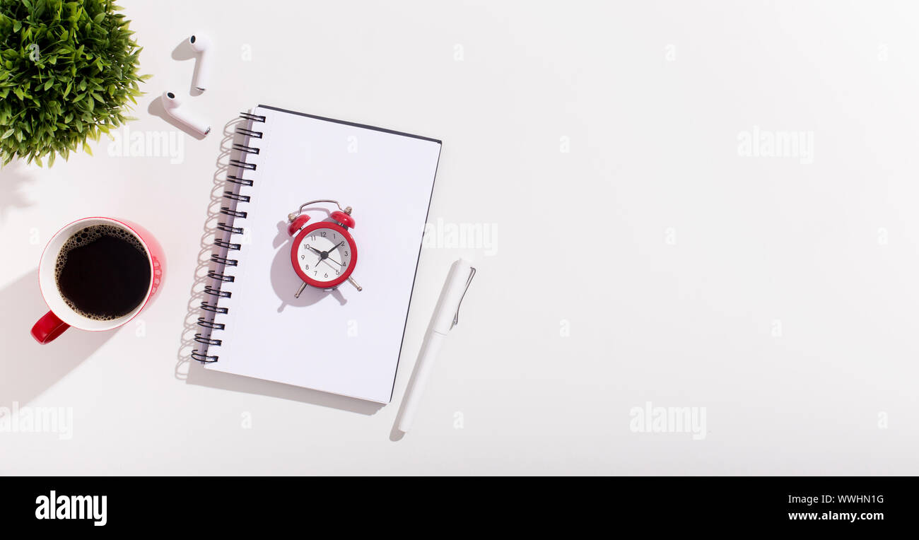 Alarm clock on notebook and coffee cup on white Stock Photo