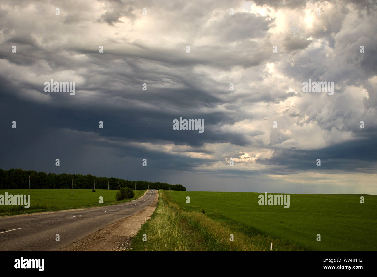 country road along the field under heavy clouds Stock Photo - Alamy