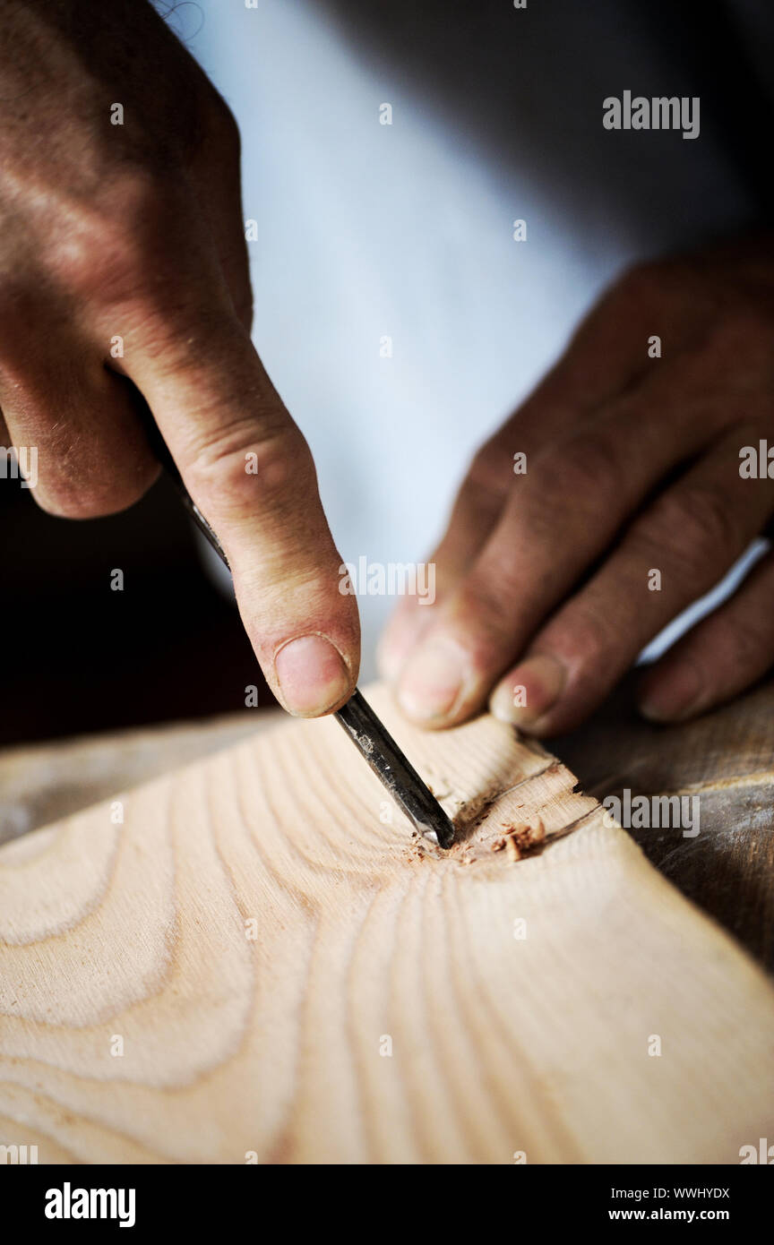 hands of the craftsman carve a bas-relief with a gouge Stock Photo