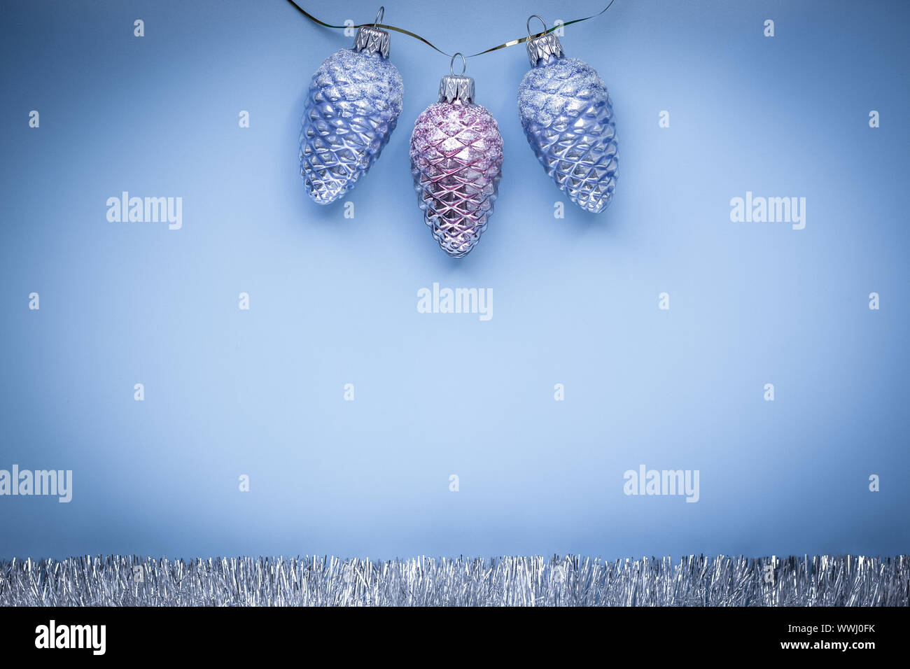 Happy new year greeting card. Text space. Christmas decoration on blue paper background. Festive cones and silver garland. Laconic creative modern des Stock Photo