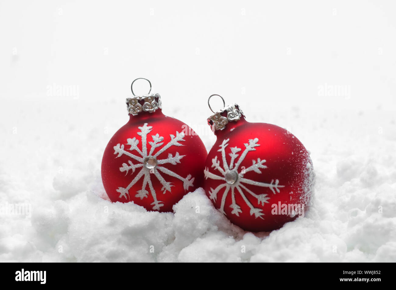 Red Christmas balls in snow on white background Stock Photo - Alamy