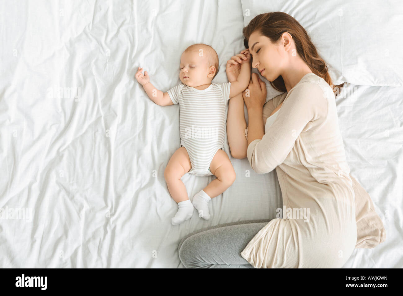 Mother and her adorable newborn baby sleeping in bed together Stock