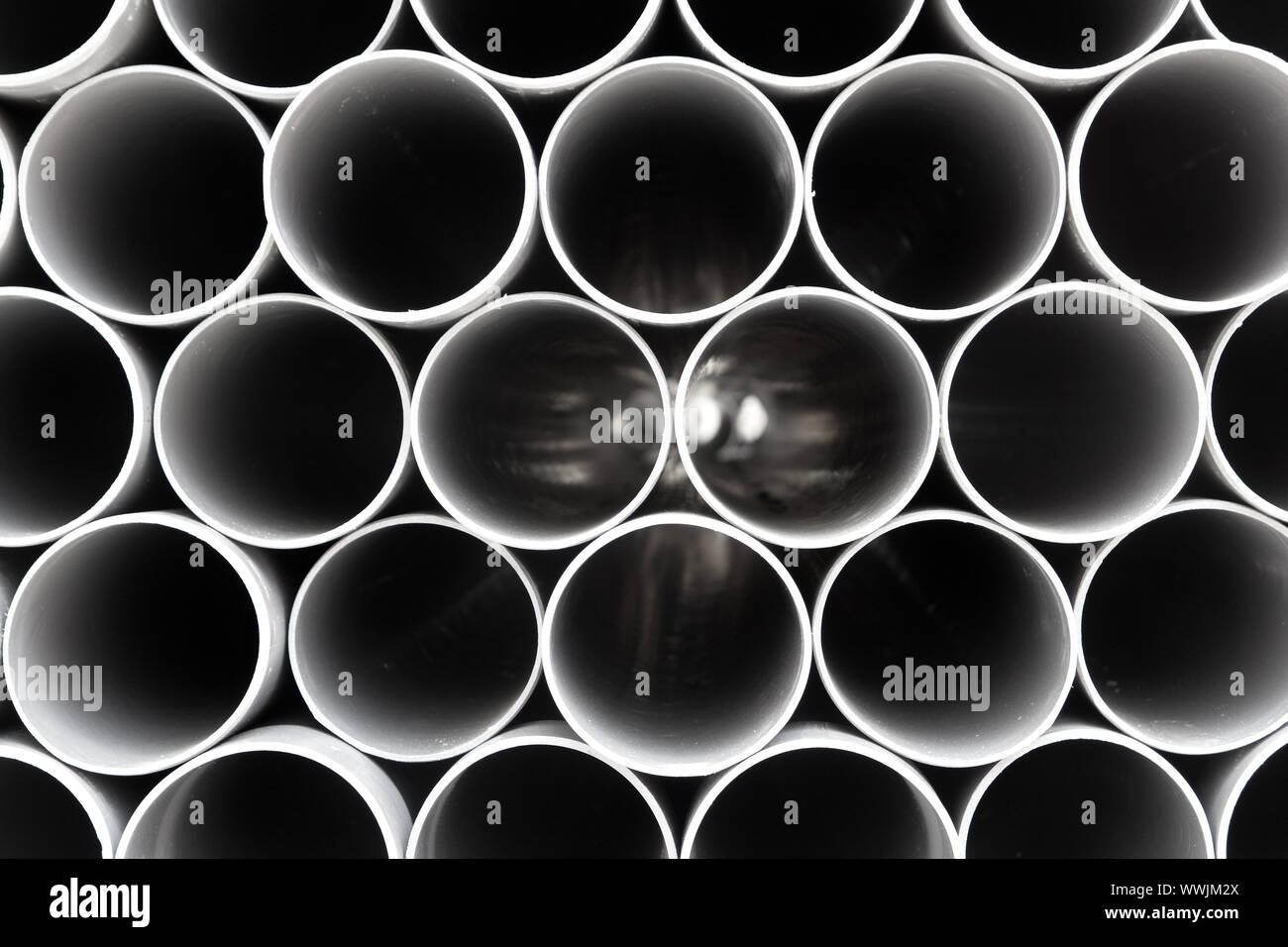 gray PVC tubes plastic pipes stacked in rows pattern Stock Photo