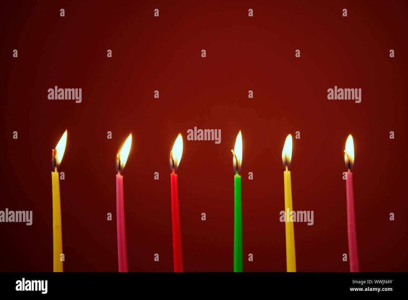 Colorful birthday light candles in a row red background Stock Photo - Alamy