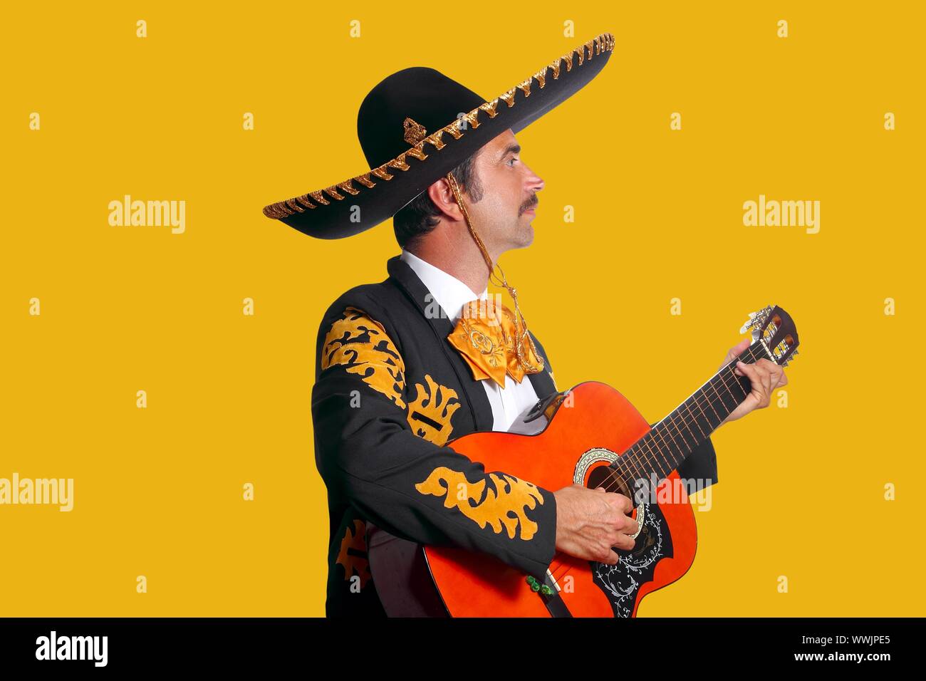 Charro Mariachi man playing guitar on yellow background Stock Photo