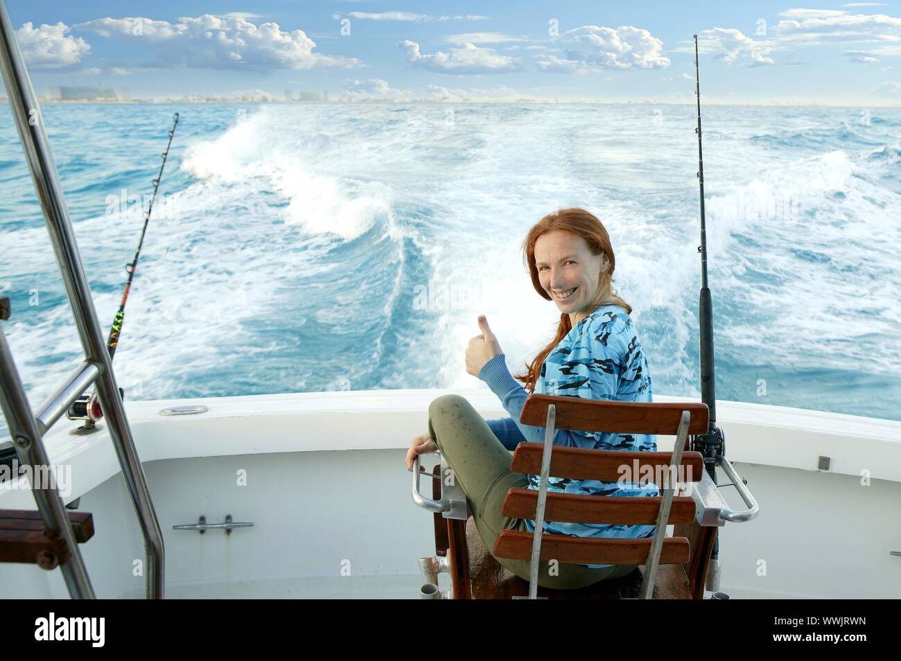 fisherwoman big game on boat chair ok sign happy Stock Photo