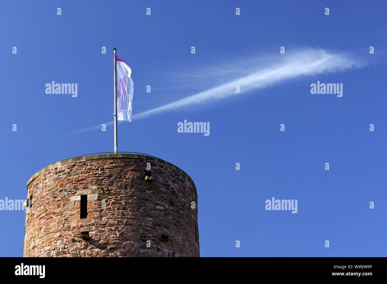 The flag of the International Academy of Fine Arts Heimbach is flying over the keep of the castle Hengebach in Heimbach. Stock Photo