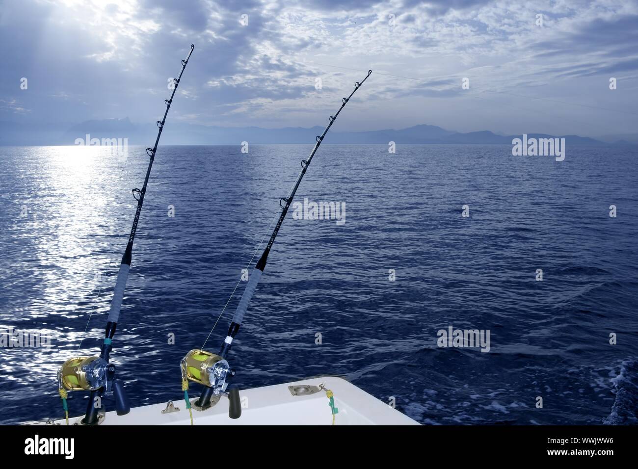 Fishing boat trolling with two rods and reels on blue ocean Stock