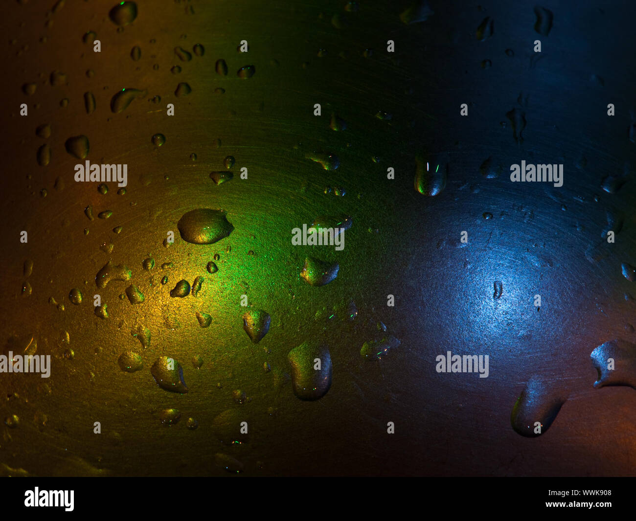 Gotas de agua sobre superficie metálica iluminada con luces de colores Stock Photo