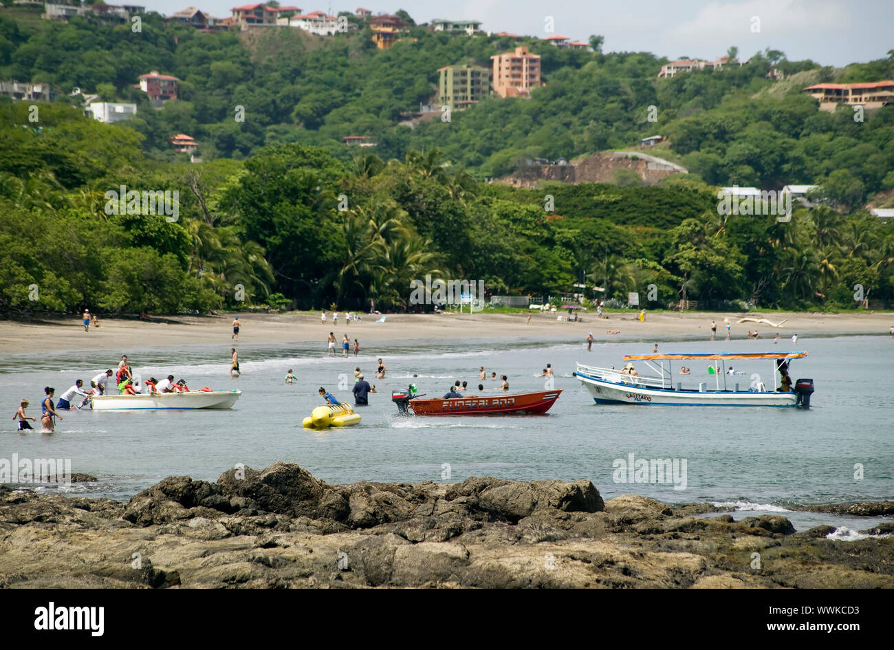 People and boats in the water at Playa Hermosa Costa Rica Stock Photo