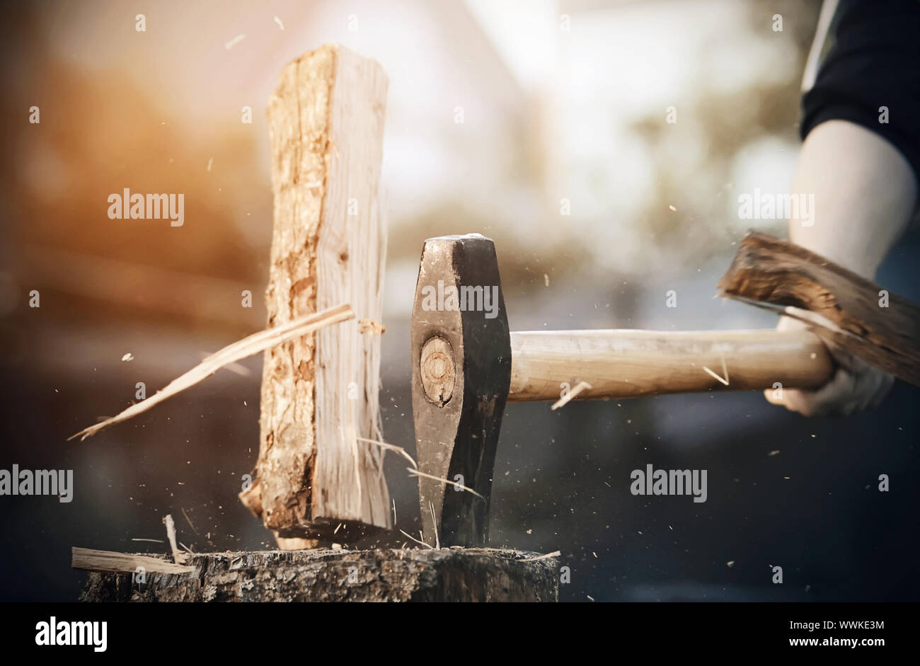 A powerful sharp axe cuts a log into pieces, from which small and large splinters fly in all directions. Stock Photo