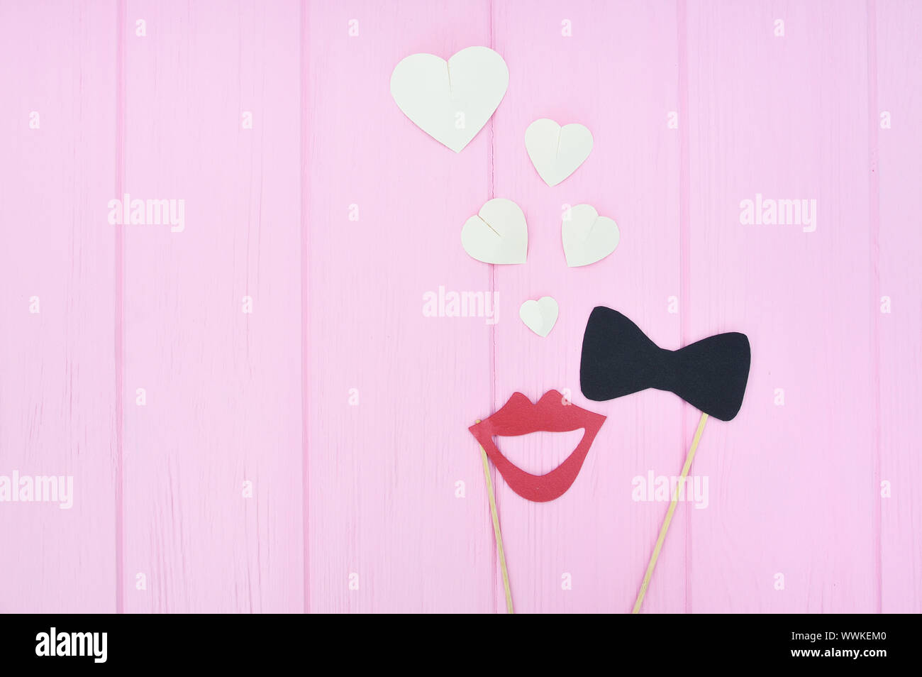 concept of man and woman fallen in love. Female lips and bow-tie with hearts on a pink wooden background with place for text. Idea for wedding Stock Photo
