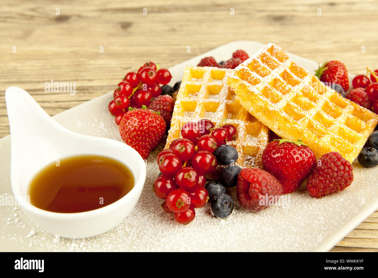 Fresh waffles with icing sugar and berries on one table Stock Photo