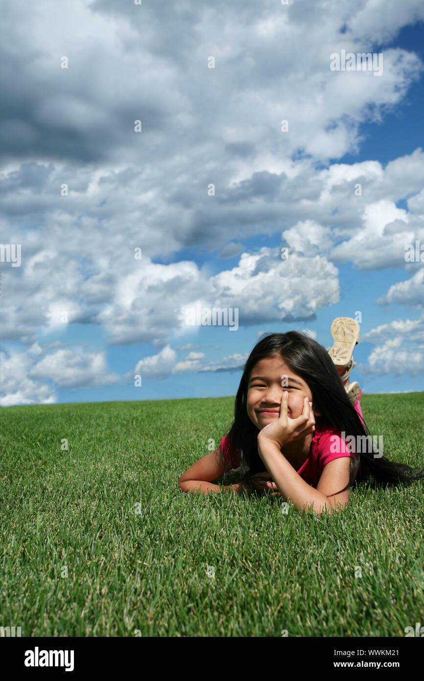 Little girl lying on grass in summer Stock Photo - Alamy