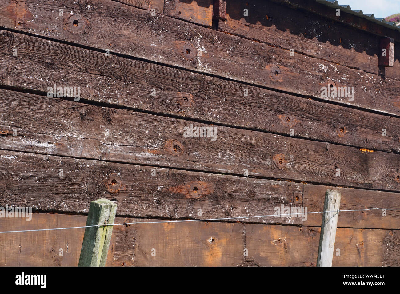 A close up view of reclaimed timber reused to build a timber barn showing the old bolt holes, the grain and thickness and quality of the timber boards Stock Photo