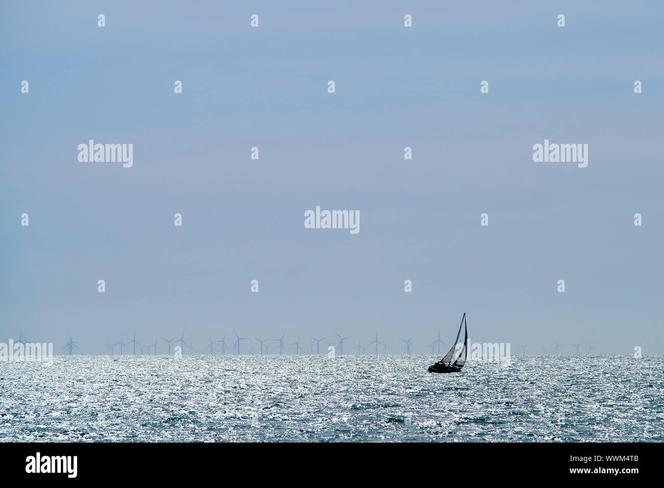 Sailing boat in front of Rampion offshore wind turbines in the English Channel. Stock Photo