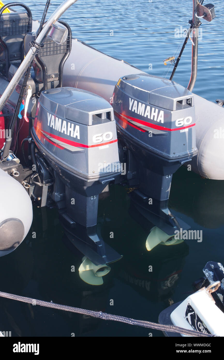 A pair of Yamaha 60 outboard motors on the back of a dinghy with a fishing rod in view Stock Photo